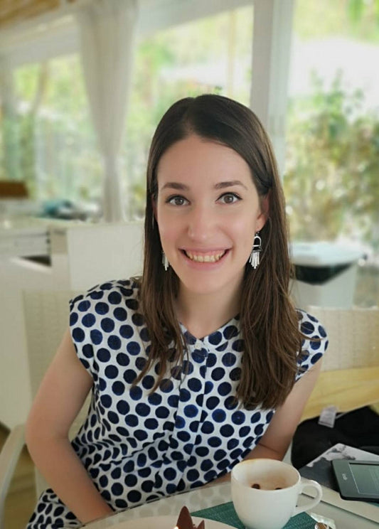 [ unused0 ], a young woman with dark brown hair, wearing a blue and white polka dot dress, smiles at the camera.